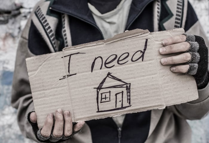 Homeless man holding sign that says "I need a home"