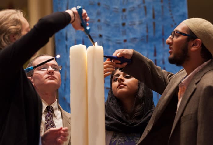 Young adults from different faiths lighting candles during a Sacred Song service