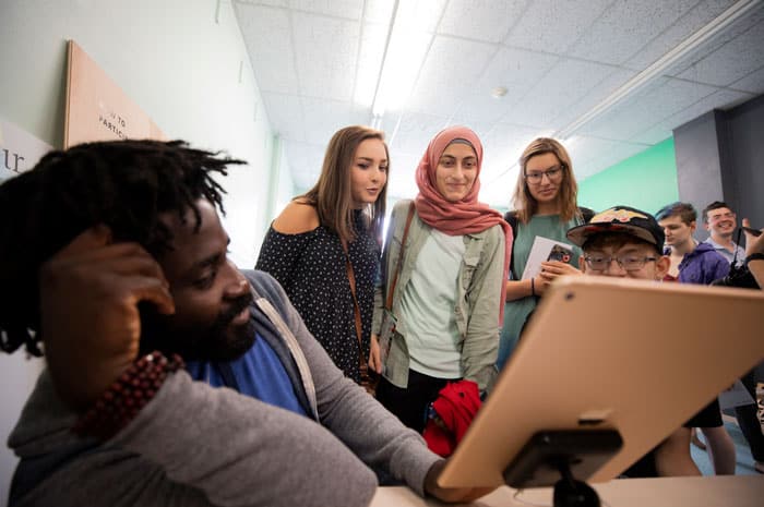 Teens gathering around an iPad in the Poetry Makerspace