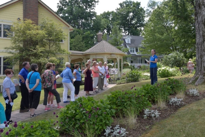 People listening to Betsy Burgeson talk about the gardens at the President's Cottage during the House and Garden Tour