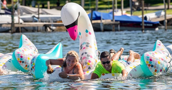 two people on a inflatable swan water racing