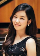 HaEun Yang in a black dress sitting at a piano