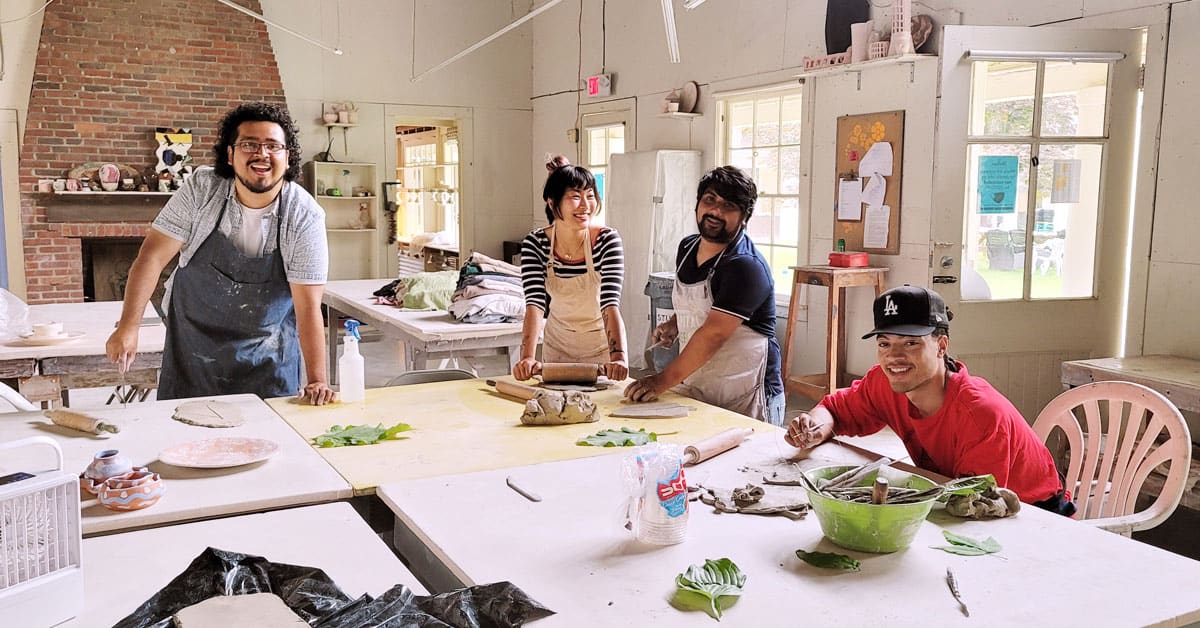 Four art students working on ceramics in a studio