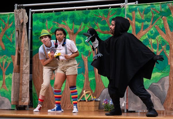 Hansel and Gretel looking in hesitation at a black bird during a performance