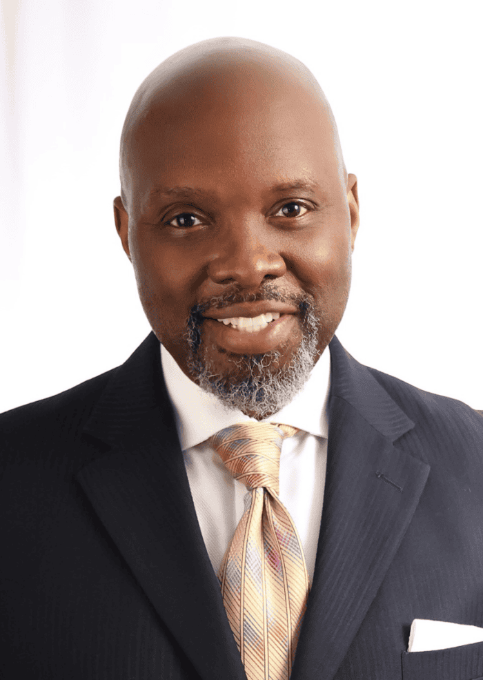 DeJeanette Horne headshot. He wears a multicolored tie, white shirt with a suit jacket.