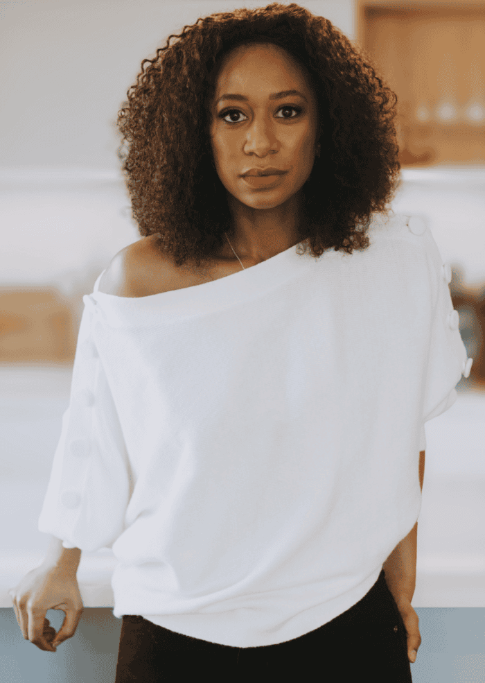 Sharina Martin headshot. She has brown curly hair to her shoulders and she wears a white short sleeve shirt with black pants.