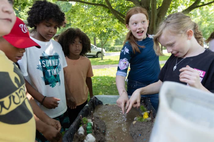 Students gathered around a tub of muddy water