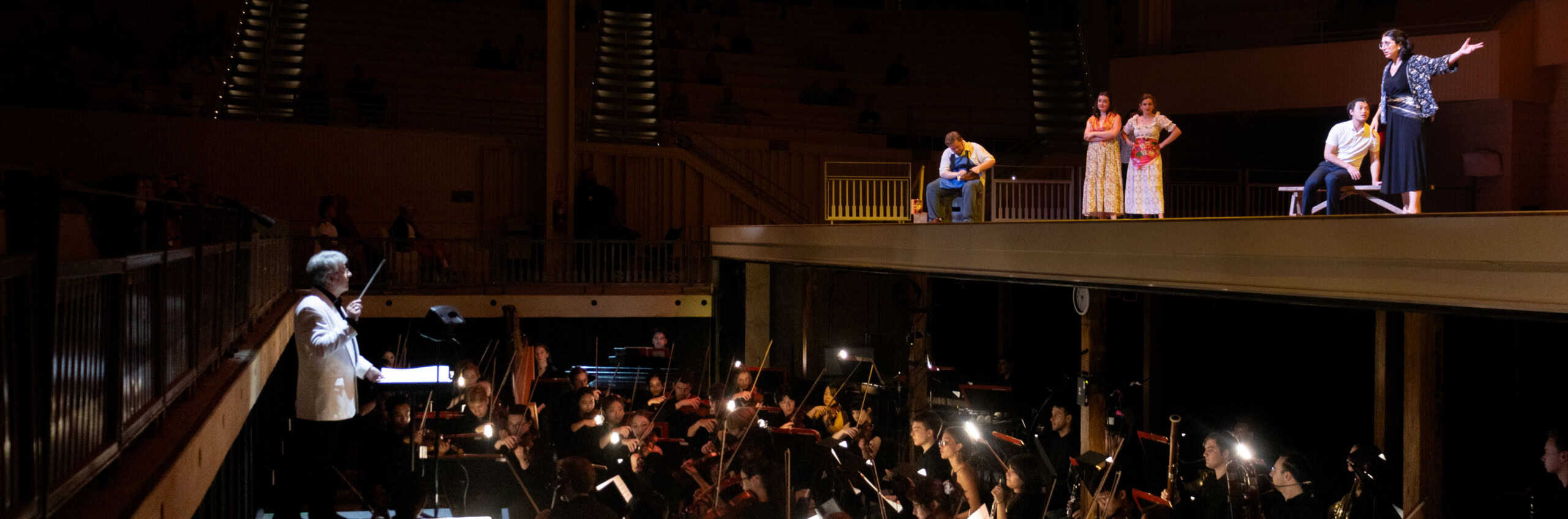 Students singing on the Amphitheater stage while the orchestra is playing in the pit