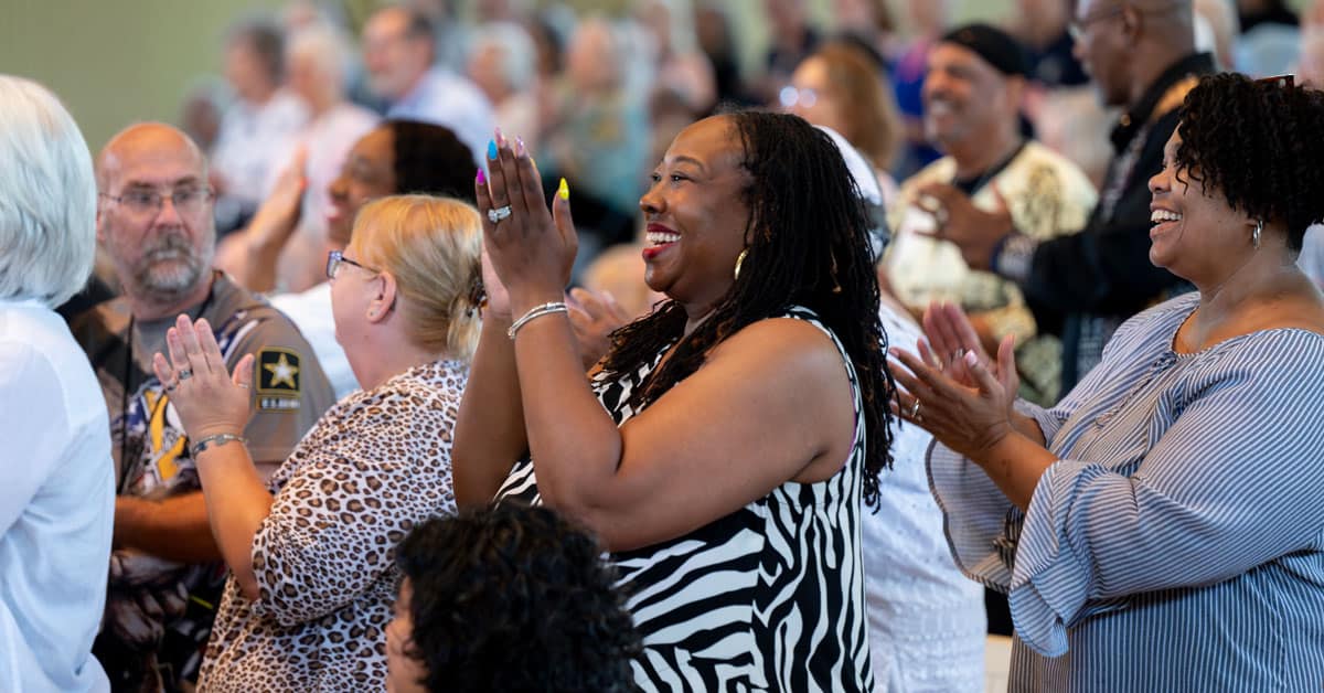 People smiling and clapping during worship