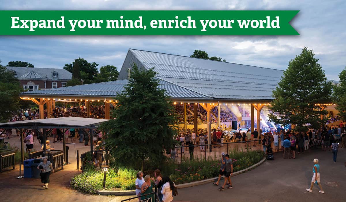 A crowded amphitheater during a concert and a banner that says Expand your mind enrich your world