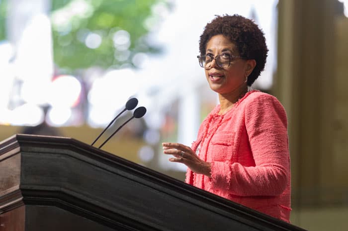 A woman in a pink blazer giving a lecture