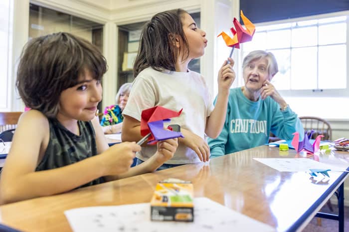 Two boys and their grandma taking an origami class