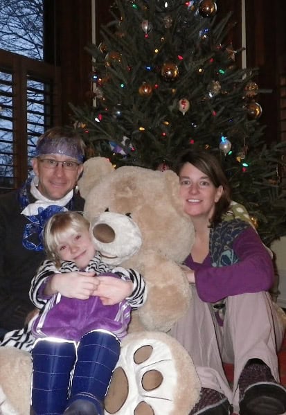 Mark, Nina, and Dare Wenzler sitting with a large teddy bear in front of a Christmas tree