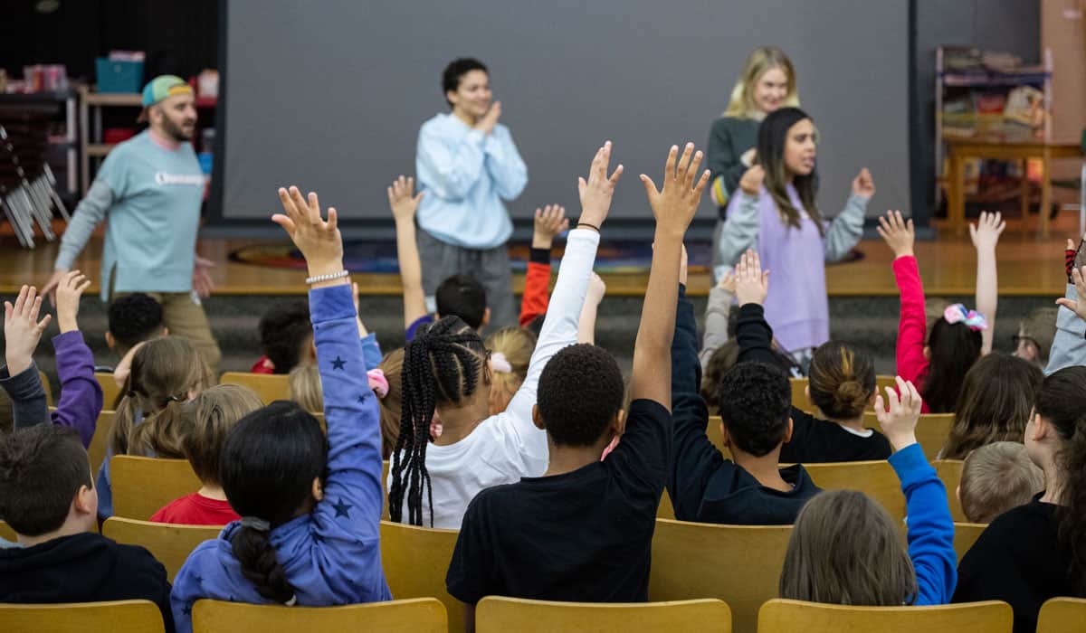 Students raising their hands in an auditorium