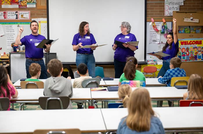 Four volunteers reading plays in front of a class of students