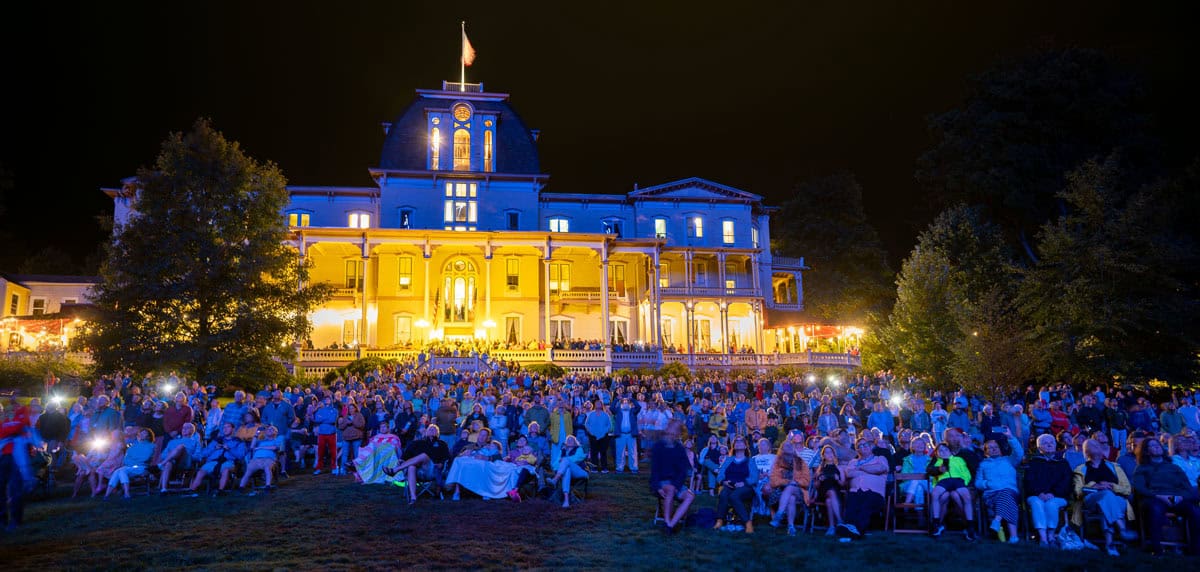 People watching a drone show at night in front of the Athenaeum Hotel